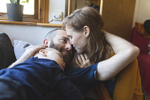 Affectionate family on the sofa with sleeping little son - WPEF02491