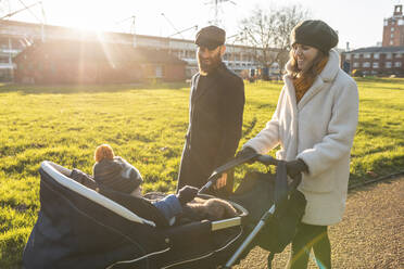 Happy couple with little son in a pushchair at park - WPEF02503