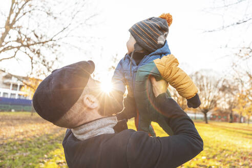 Mann hebt seinen kleinen Sohn im Park hoch - WPEF02509