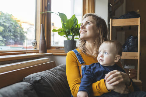 Mutter und Sohn auf dem Sofa mit Blick aus dem Fenster, lizenzfreies Stockfoto