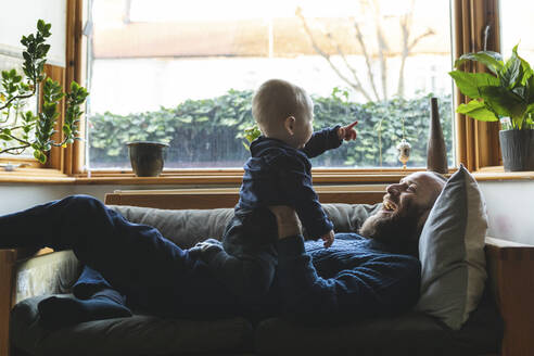 Mann spielt mit seinem kleinen Sohn auf dem Sofa - WPEF02520