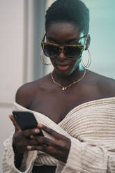 Porträt einer jungen Frau mit Sonnenbrille und Smartphone - MPPF00444