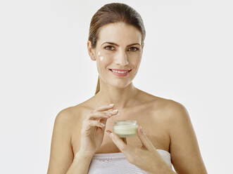 Portrait of smiling woman with cream jar - RORF01987