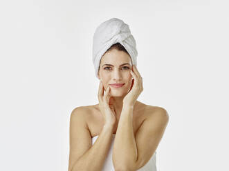 Portrait of smiling woman with hairs wrapped in towel against white background - RORF01991