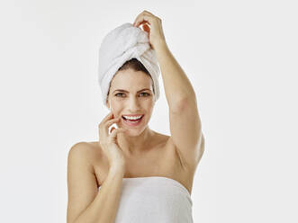 Portrait of happy woman with hairs wrapped in towel against white background - RORF01993