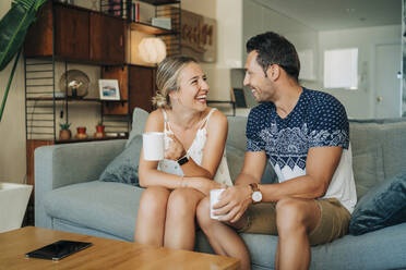 Happy relaxed couple sitting on couch in living room - MPPF00457