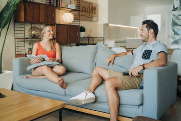 Glückliches Paar sitzt auf der Couch im Wohnzimmer - MPPF00475