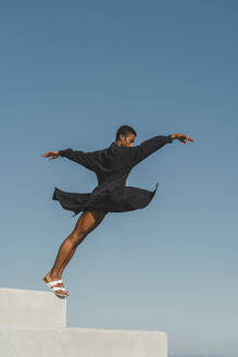 Young man wearing black kaftan performing outdoors - AFVF05160