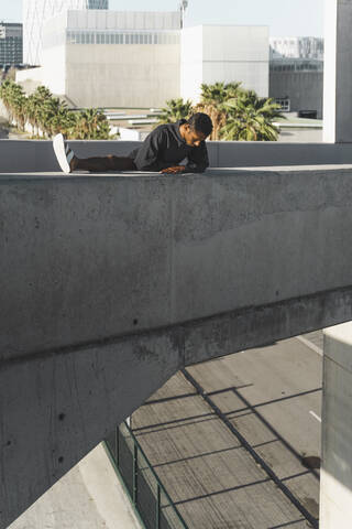 Young man wearing black kaftan climbing on a concrete wall stock photo