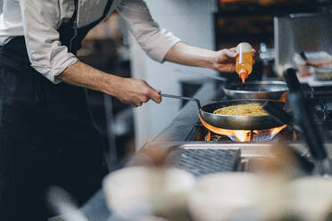 Chef preparing a dish in traditional Italian restaurant kitchen - OCAF00445