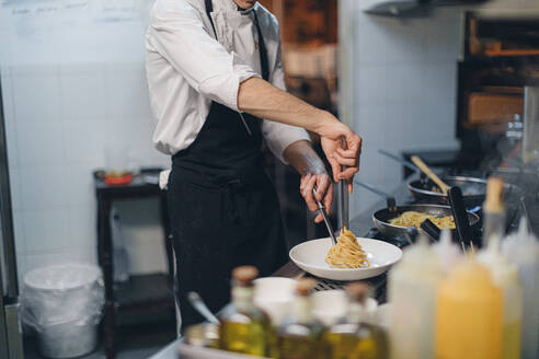 Koch bei der Zubereitung eines Nudelgerichts in einem traditionellen italienischen Restaurant - OCAF00450