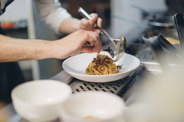 Chef preparing a dish in traditional Italian restaurant kitchen - OCAF00451