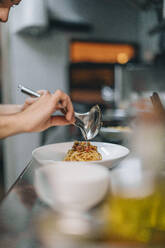 Chef preparing a dish in traditional Italian restaurant kitchen - OCAF00453