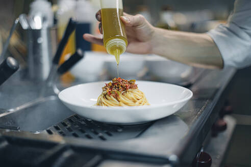 Koch bei der Zubereitung eines Gerichts in einer traditionellen italienischen Restaurantküche - OCAF00455