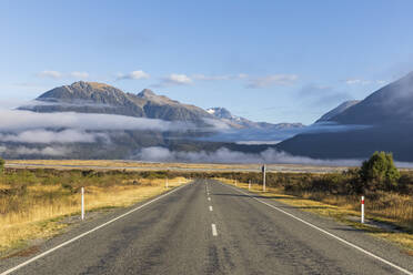 Neuseeland, Nebel über dem leeren State Highway 73 mit Bergen im Hintergrund - FOF11564