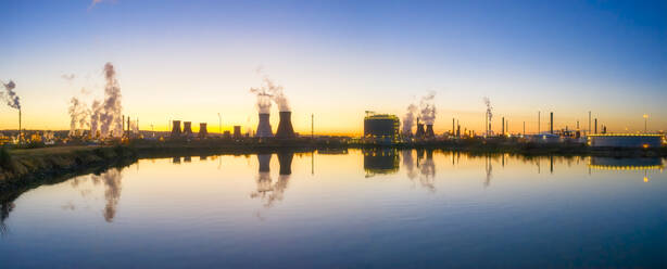 UK, Scotland, Grangemouth, Cooling towers of Grangemouth Refinery reflecting in coastal water of Firth of Forth at sunset - SMAF01729