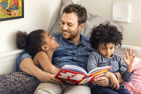 Vater liest Kindern ein Buch vor - JOHF05745