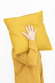 Mann mit gelbem Pullover versteckt Gesicht hinter gelbem Kissen - MCVF00197