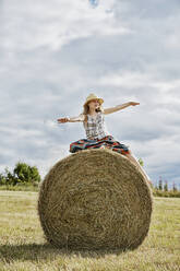 Girl sitting on bale of hay - JOHF05965