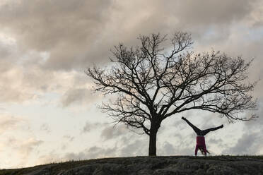 Silhouette einer Frau im Handstand - JOHF06050