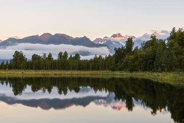 Neuseeland, Westland District, Fox Glacier, Lake Matheson mit Spiegelung des umgebenden Waldes und der entfernten Bergkette - FOF11576