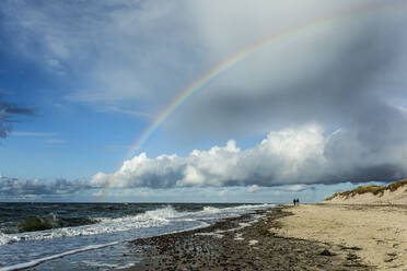 Germany, Mecklenburg-West Pomerania, Prerow, Rainbow against cloudy sky over sandy coastal beach - STBF00527