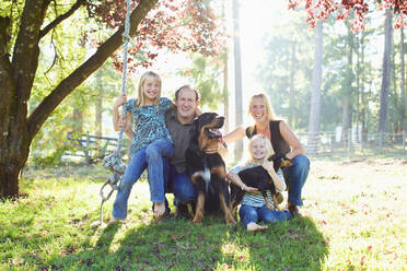 Portrait glückliche Familie mit Hunden im sonnigen Herbstpark - FSIF04545