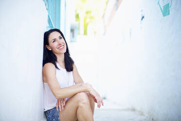Portrait smiling, confident woman relaxing in summer alley - FSIF04549