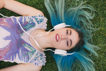 Overhead portrait young woman with blue hair listening to music with headphones - FSIF04581