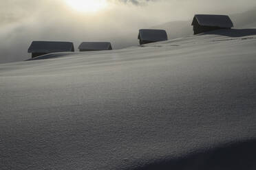 Verschneite Hütten am sonnigen, ruhigen Berghang, Vella, Kanton Graubünden, Schweiz - FSIF04594