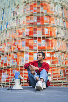 Portrait of mature man with megaphone sitting outdoors, Barcelona, Spain - AFVF05225