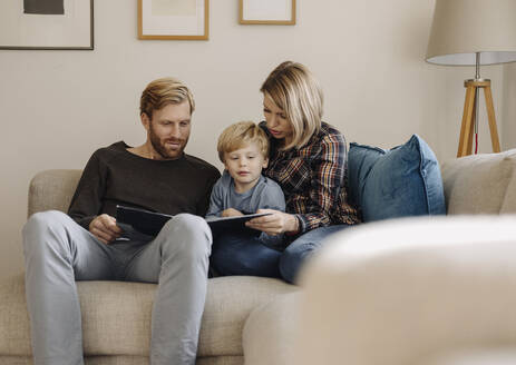 Familie schaut sich auf der Couch zu Hause ein Buch an - KNSF07010