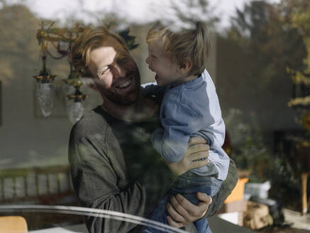 Glücklicher Vater mit Sohn am Fenster zu Hause - KNSF07022