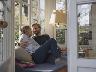 Affectionate couple relaxing in sunroom at home - KNSF07034