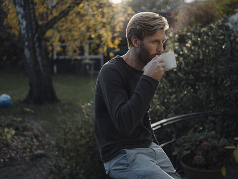 Man having a coffee break in garden stock photo