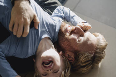 Glücklicher Vater und Sohn kuscheln zu Hause auf dem Boden - KNSF07070