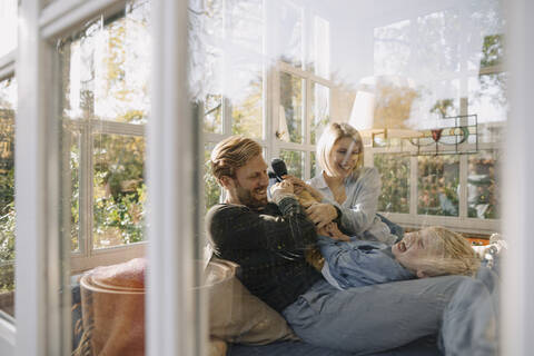 Glückliche Familie hat Spaß im Sonnenzimmer zu Hause, lizenzfreies Stockfoto