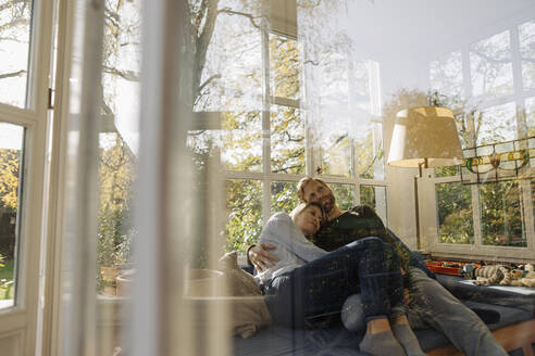 Affectionate couple relaxing in sunroom at home - KNSF07081