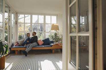 Affectionate couple relaxing in sunroom at home - KNSF07082