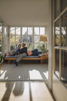 Affectionate couple relaxing in sunroom at home - KNSF07083