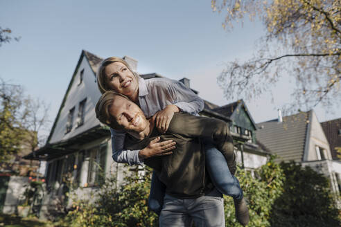 Man giving his wife a piggyback ride in garden - KNSF07095