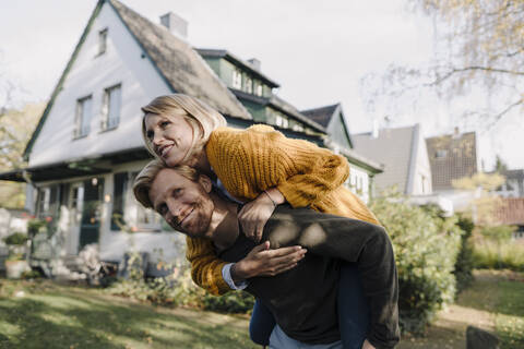 Mann reitet seine Frau im Garten huckepack, lizenzfreies Stockfoto