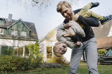 Glücklicher Vater spielt mit seinem Sohn im Garten - KNSF07138