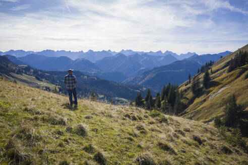 Austria, Tyrol, Eben am Achensee, Male hiker admiring green forested mountains in autumn - DHEF00054