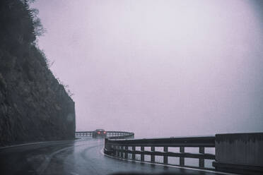 Italy, South Tyrol, Bolzano, Winding highway in rain and fog - DHEF00055