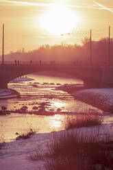 Deutschland, Bayern, München, Bogenbrücke bei stimmungsvollem Wintersonnenuntergang - DHEF00058