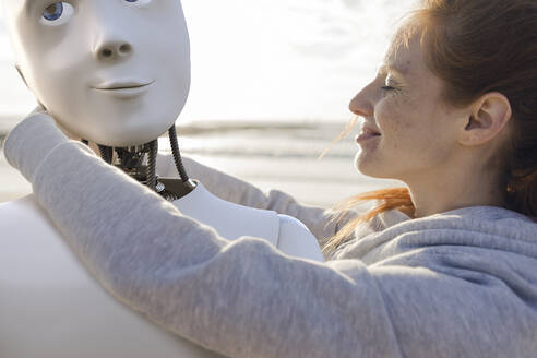Glückliche Frau umarmt Roboter am Strand - KSHSF00026