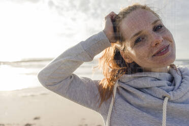 Porträt einer lächelnden Frau am Strand mit Gitter über seinem Gesicht - KSHSF00029