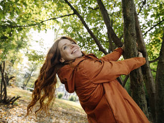 Happy redheaded woman enjoying autumn in a park - KNSF07155