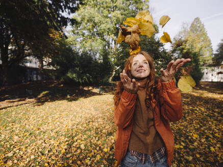Glückliche rothaarige Frau genießt den Herbst in einem Park - KNSF07158